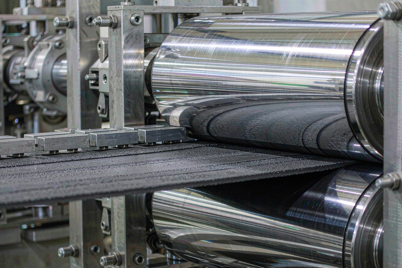 Sodium-ion battery calendering process compressing hard carbon electrode coating between polished steel rolls for porosity control