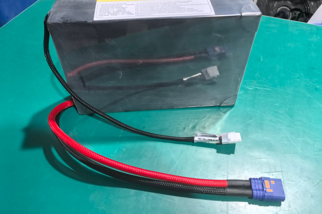 Assembled drone battery pack with braided power leads and connector on a workbench